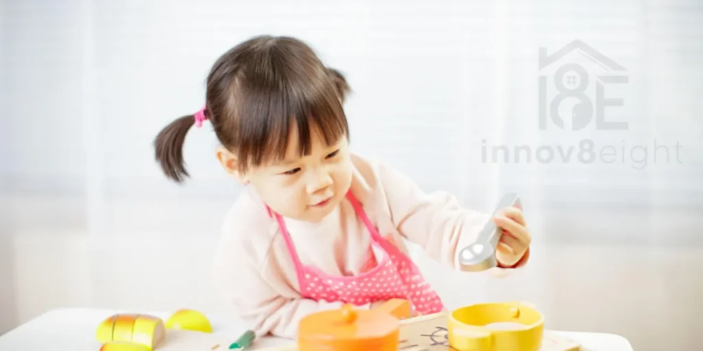 Young girl playing with a girls kitchen set, chopping pretend vegetables on a toy cutting board